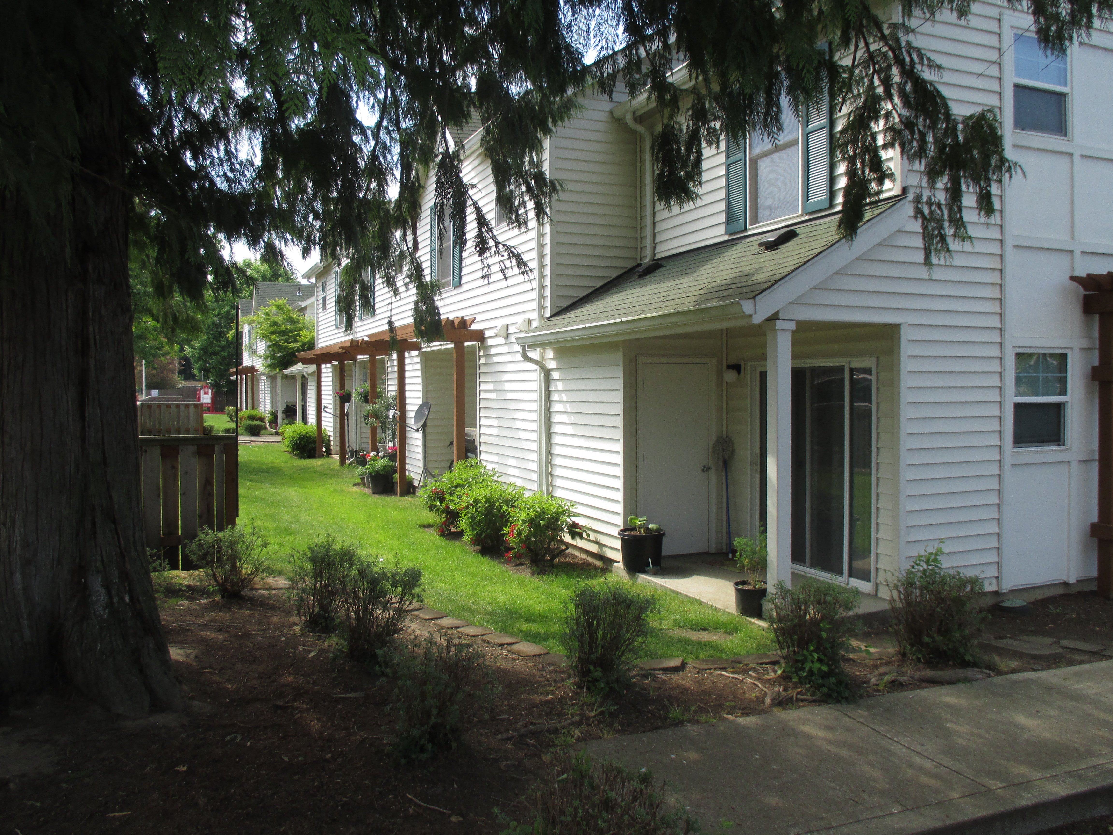 a row of white houses with a lawn and trees